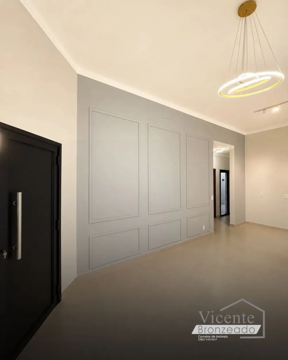 Entrada da casa com porta pivotante preta e parede decorada com boiserie