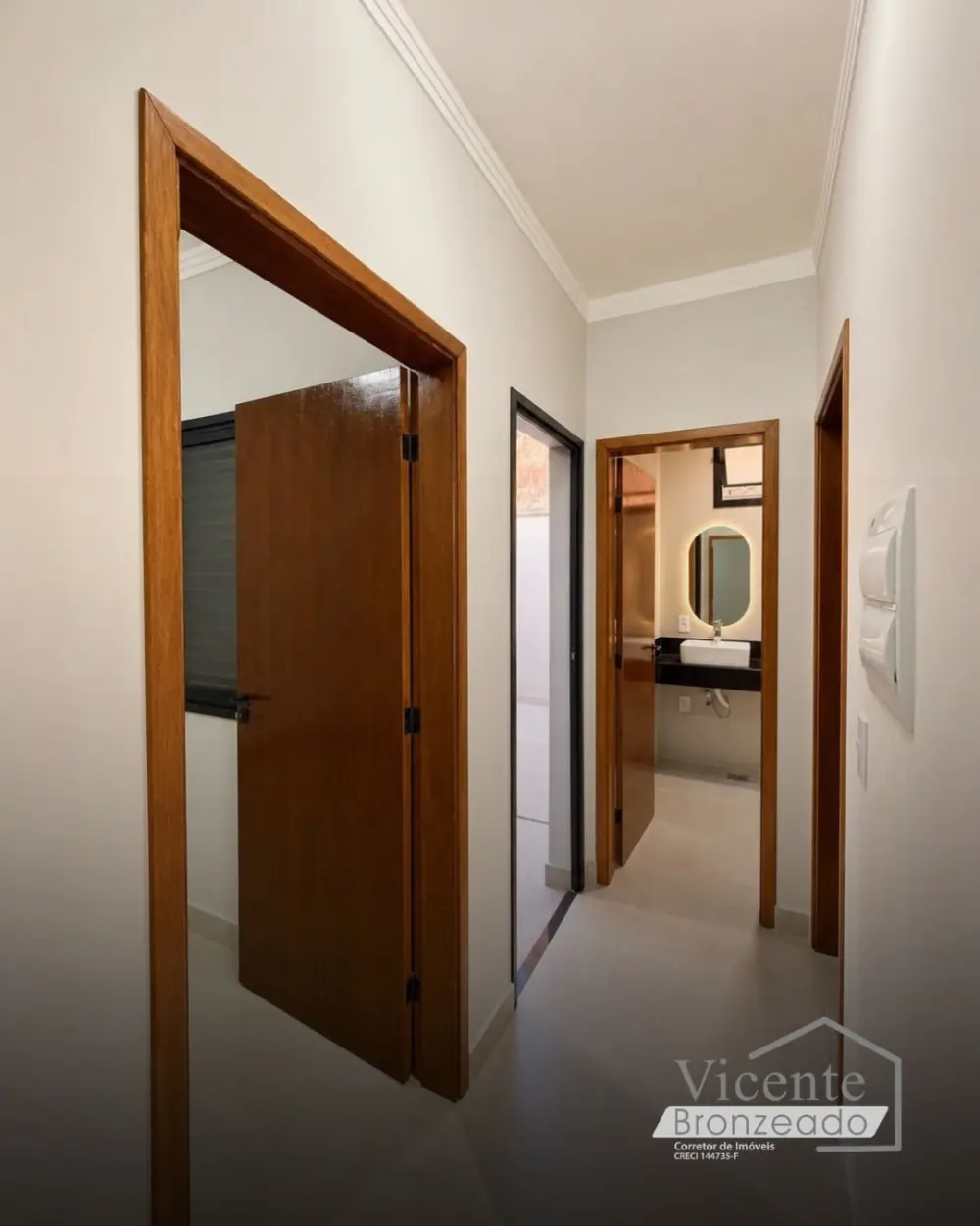 Corredor com portas de madeira e lavabo com espelho iluminado ao fundo