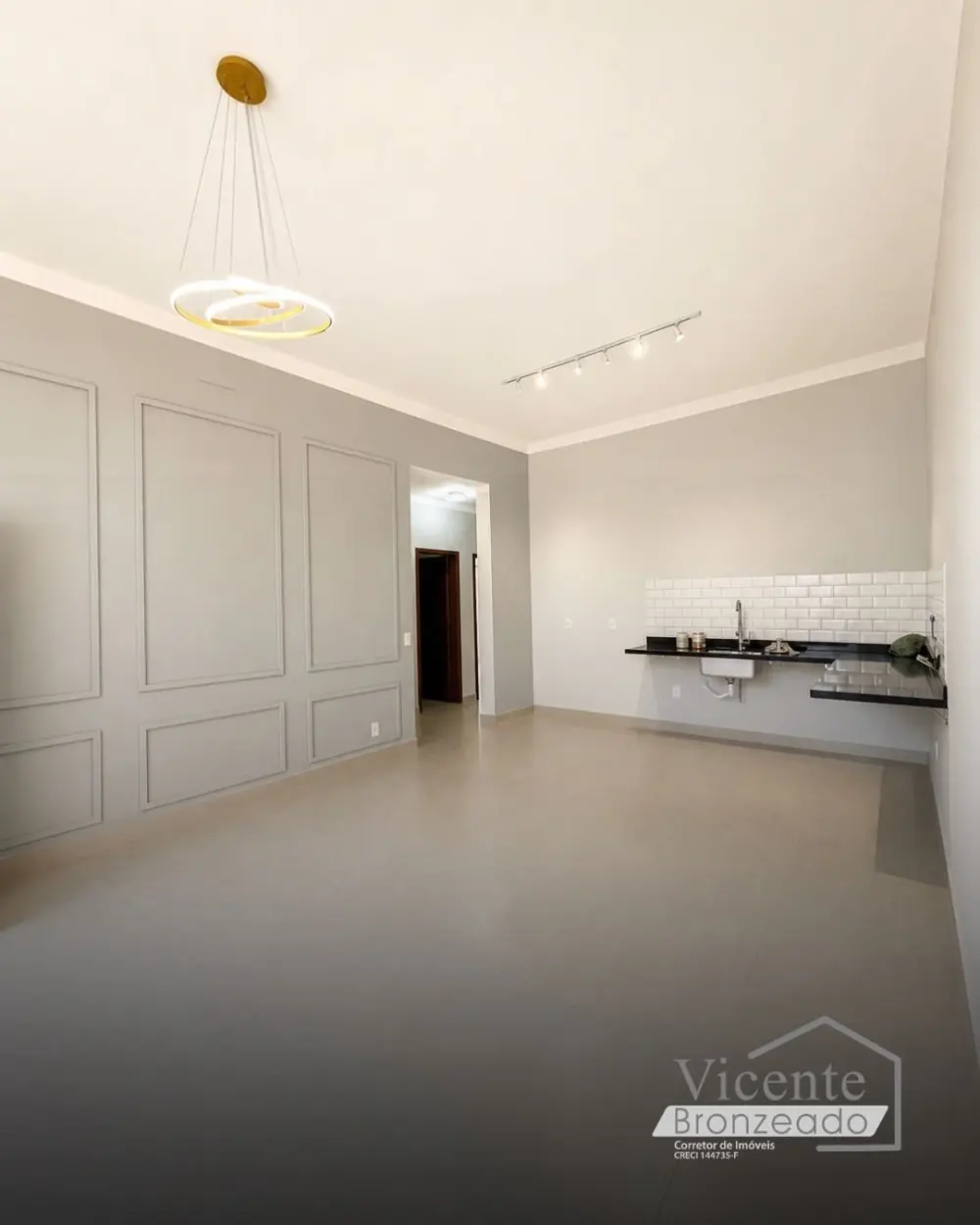 Sala ampla com parede boiserie, lustre moderno e bancada de cozinha em granito preto