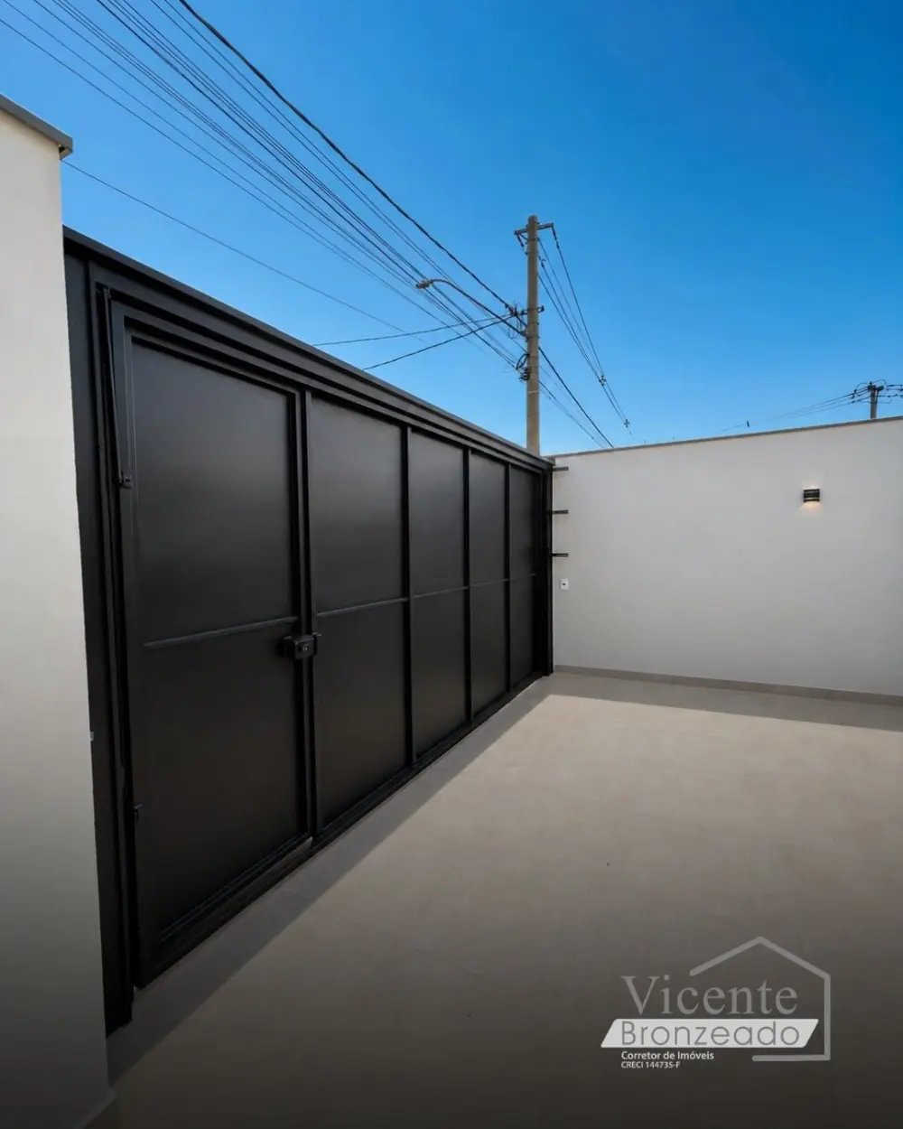 Garagem coberta com portão basculante preto e piso porcelanato