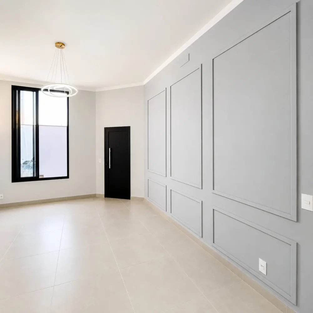 Sala de estar com parede boiserie cinza, lustre de anéis e porta pivotante preta